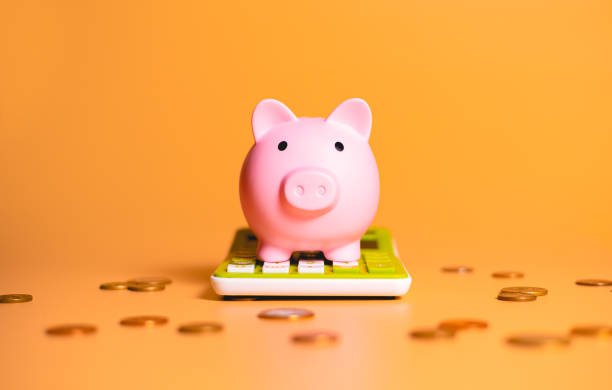 Piggy Bank sitting on top of a Calculator with coins lying around